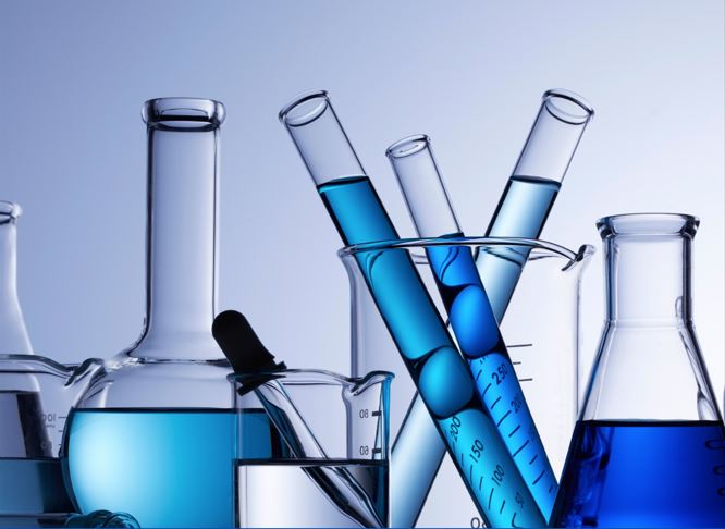 djęcie probówek i naczyń laboratoryjnych z niebieskimi cieczami.